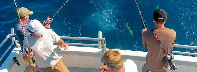 Party boat group share charter staying in Buxton standing at transom of Stormy Petrel catching some OBX mahi.